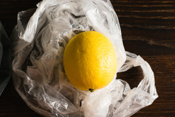Earth day, recycling and zero waste concept. Lemon in a plastic bag on a dark background