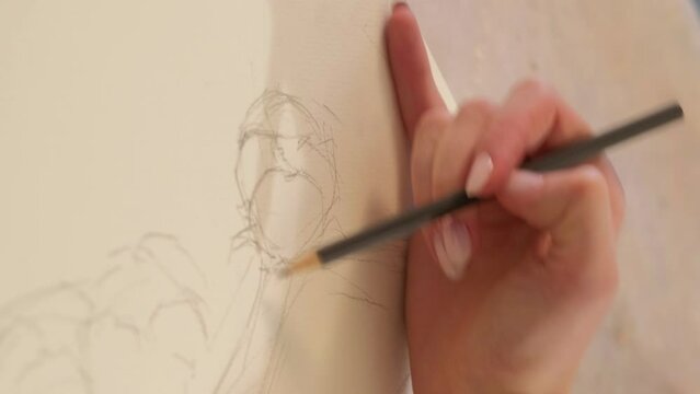 Vertical video. Artwork drawing. Creative process. Painting art. Closeup of female artist hand sketching line with pencil on canvas.