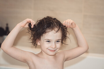 Smiling girl with wet tousled hair in the bathroom. The concept of childhood, happiness, hygiene