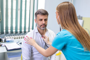 Young doctor is using a stethoscope listen to the heartbeat of the patient. Shot of a female doctor giving a male patient a check up