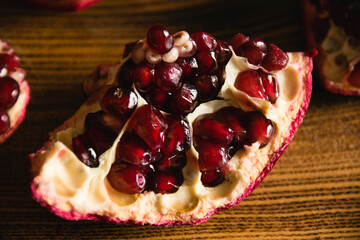 Appetizing piece of sweet pomegranate macro on cutting board on dark background