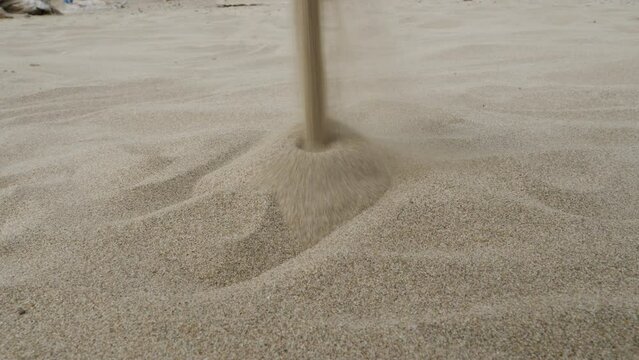 Falling white sand forms a pile on the beach