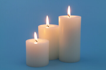 Scented candles burning on blue background close-up.	