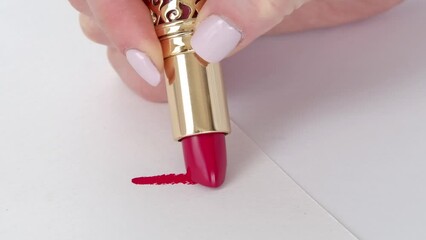 A woman's hand with new red lipstick making a mark on a white background is an example of a color, advertisement template.