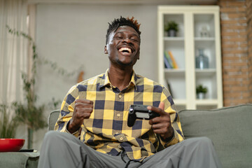 Young happy African guy playing video game at home. Man holding joystick and playing video games..