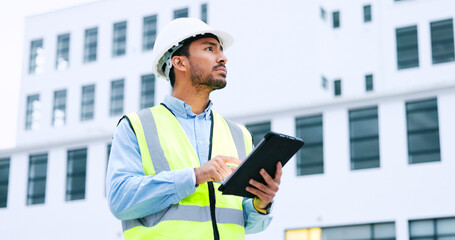 Male engineer checking data on digital tablet and inspecting construction site. Technician in a...