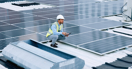 Engineer or contractor measuring solar panels on a roof of a building. Engineering technician or electrician installing alternative clean energy equipment and holding a tablet to record measurements