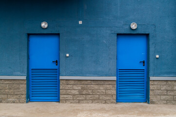 two blue metal entrance doors and part of the wall