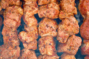 Grill barbecue meat on brazier with smoke. Cooking meat on brazier. Meat sticks cooked at barbecue, close up. Shish kebab cooking outdoors..