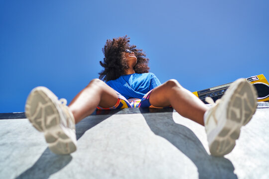 Carefree young woman with boom box at edge of sports ramp