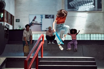 Deurstickers Young woman doing skateboard stunt at skateboard park © Caia Image