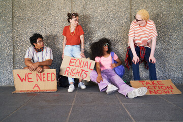 Young friends with equal rights signs resting at wall