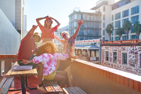 Portrait happy young friends cheering on sunny city rooftop