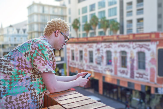 Young man using smart phone on urban balcony - Powered by Adobe
