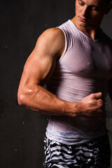 Fototapeta na wymiar Athlete bodybuilder trains in the studio in the rain.