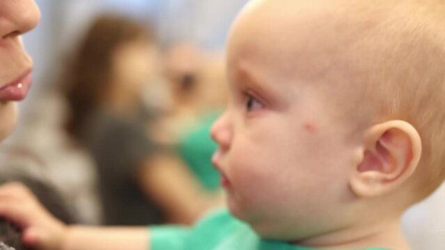close-up portrait baby toddler face eyes full of tears, child on mothers hands, embarrass loving kid. brunette mom talking to her baby green shirt, child looking into parents eyes emotions together 