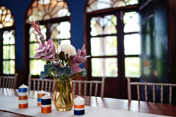 Yellow glass vase with many flowers placed on wooden table
