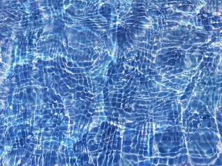 Defocus blurred transparent blue colored clear calm water surface texture with splashes and bubbles. Trendy abstract nature background. Water waves in sunlight with copy space. Blue water shine
