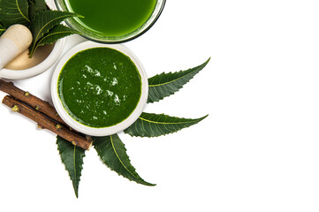 Medicinal Neem leaves in mortar and pestle with neem paste, juice and twigs on white background