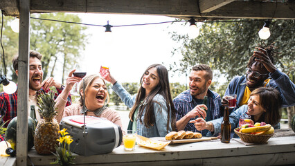 Multicultural trendy friends having fun drinking and dancing, food beverage life style concept with young millenial people at cool chiringuito on happy hour time