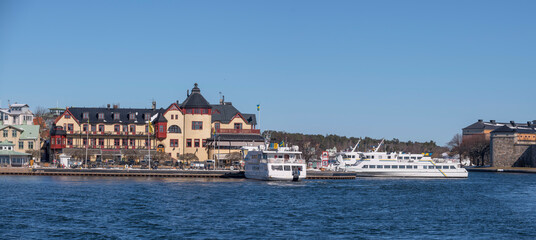 Fototapeta na wymiar Commuter archipelago ferries in the bay at the archipelago town Vaxholm, famous fortress and hotel, a sunny spring day in Stockholm