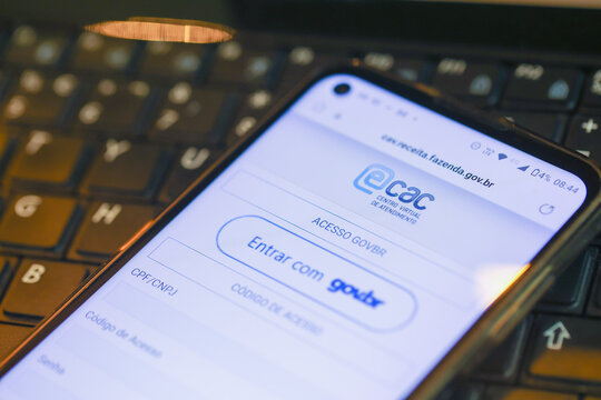 Um telefone celular sobre um teclado de um laptop mostrando a plataforma e-CAC que &eacute; o Centro Virtual de Atendimento ao Contribuinte da Receita Federal do Brasil. Bras&iacute;lia, DF - Brasil. 05/04/2023.