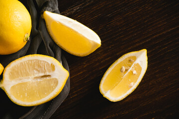 Flatlay, lemons in a fruit net, juicy pieces of lemon on a dark background. Earth day and zero...
