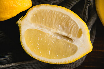 Flatlay, lemons in a fruit net, juicy pieces of lemon on a dark background. Earth day and zero...