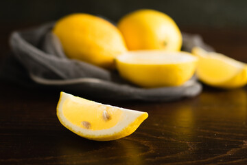 Lemons in a vegetable grid on a dark background. Slice of juicy lemon macro