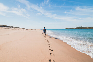 Passionate backpacker, backpack and boots in hand, walks along the Praia da Ilha do Pessegueiro...