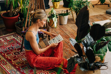 A female florist is sitting in a studio working on a tablet and shopping online.