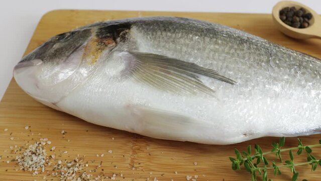 daurade enti&egrave;re, en gros plan, sur une planche &agrave; d&eacute;couper