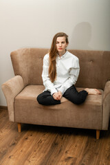 beautiful young woman with long hair sitting on a beige sofa