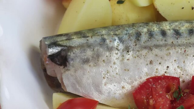 poisson (maquereau) avec pommes de terre, tomate, thym et oignons dans un plat