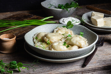 Vareniki with feta and herbs in a plate on a wooden table