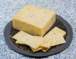 Cheese collection, piece of cow milk Dutch gouda cheese with dried aromatic cumin seeds close up