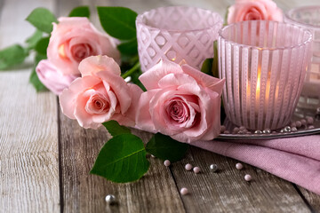 Pink roses and a candlestick on a wooden table. Postcard. Photo
