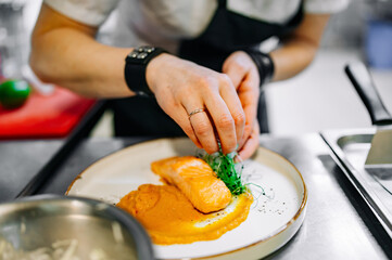 Chef cooking Roasted salmon steak with pumpkin cream on restaurant kitchen