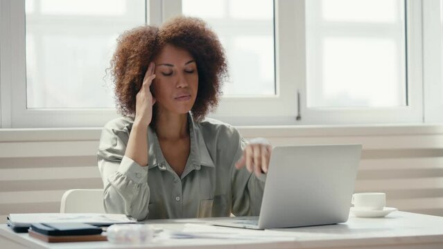 Tired African American office manager typing, suffering headache, deadlines