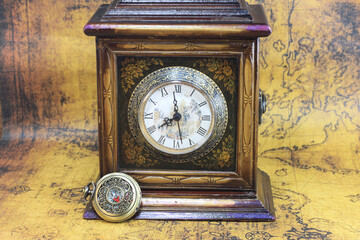 Classic round compass and old vintage clock and book on old vintage map