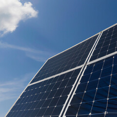 Obraz premium Blue solar panels against a blue sky with clouds. An image as a background for your creative design or illustrations. The image was created with Generative AI technology.