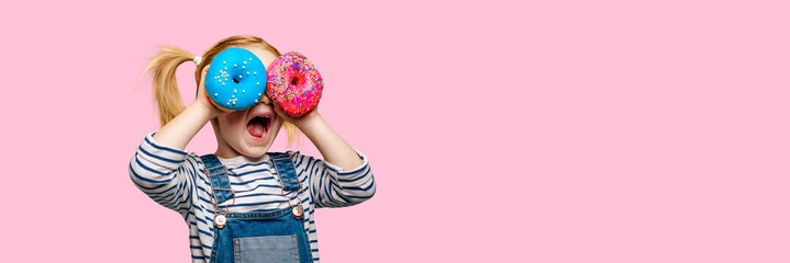 Happy cute girl is having fun played with donuts on black background wall.