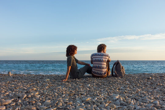 Beach summer couple on vacation. Holiday relax in the sunset with sea view at pebble beach, Idyllic travel background. High quality photo