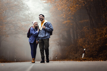 Obraz na płótnie Canvas Couple spending time together walking on forest road on a foggy morning.