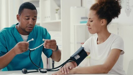 Male physician checking blood pressure of young woman patient, health check-up