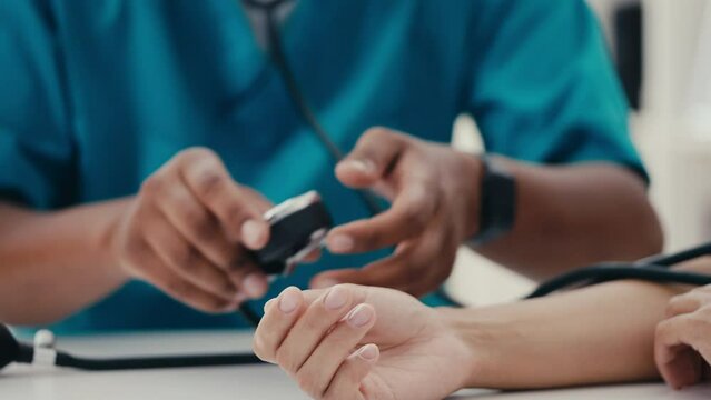 Close-up of male therapist measuring patient's blood pressure with tonometer