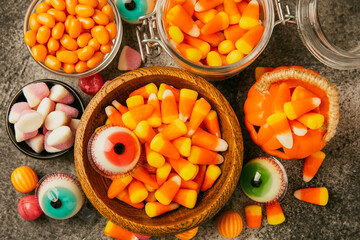 Halloween candy corn,jelly eye, pumpkin candy, sugar skull in different bowls on black background.Classic candy sweets for Halloween with.Halloween holiday concept with candy corn and jack o lantern.