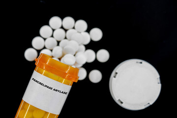 Pancrelipase Amylase Rx medical pills in plactic Bottle with tablets. Pills spilling out from yellow container.