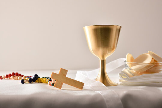 Chalice and consecrated host on table white isolated background