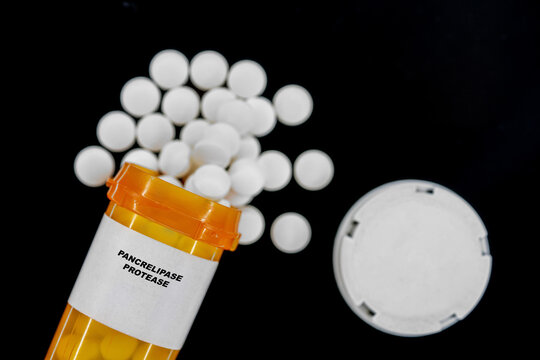 Pancrelipase Protease Rx medical pills in plactic Bottle with tablets. Pills spilling out from yellow container.